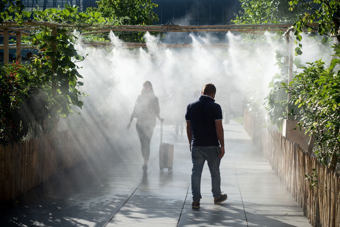 Menschen spazieren in einem Stadtpark unter einer Sprühanlage (Foto: AdobeStock)