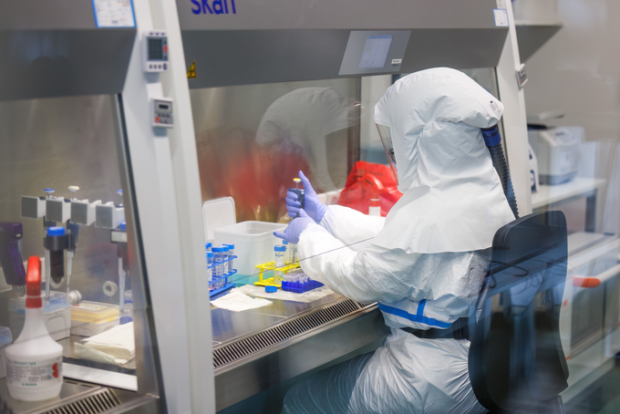 Scientist in coverall is analysing tuberculosis strains in lab.