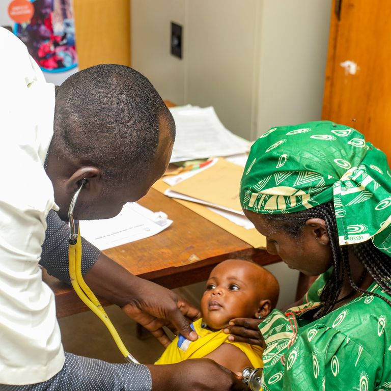 A doctor examines a child in its mother’s arms at a health centre in Chad (Photo: Fairpicture/Swiss TPH)