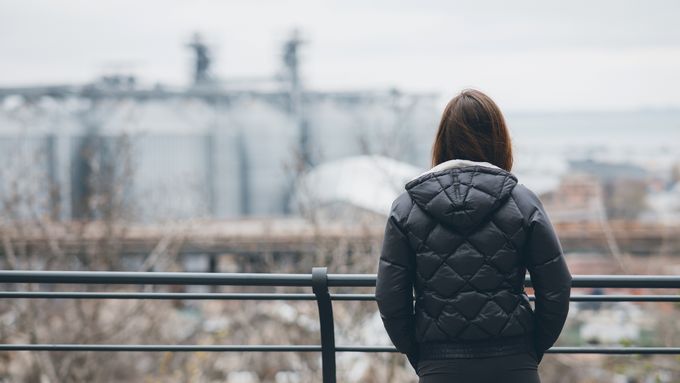 A woman is standing on a railing looking out over a city (Photo: AdobeStock)