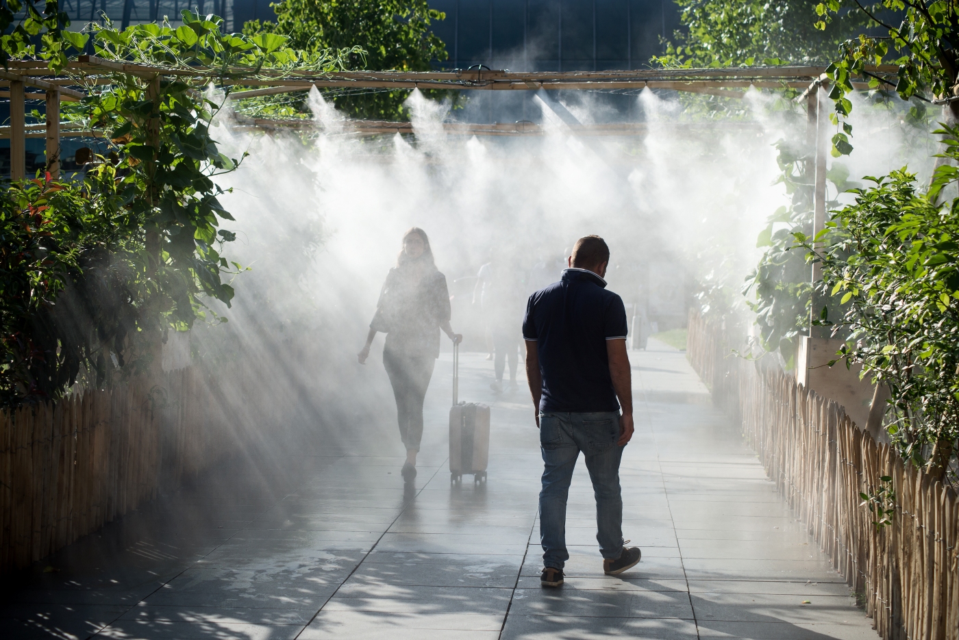 People are walking in a city park beneath a misting system (Photo: AdobeStock)