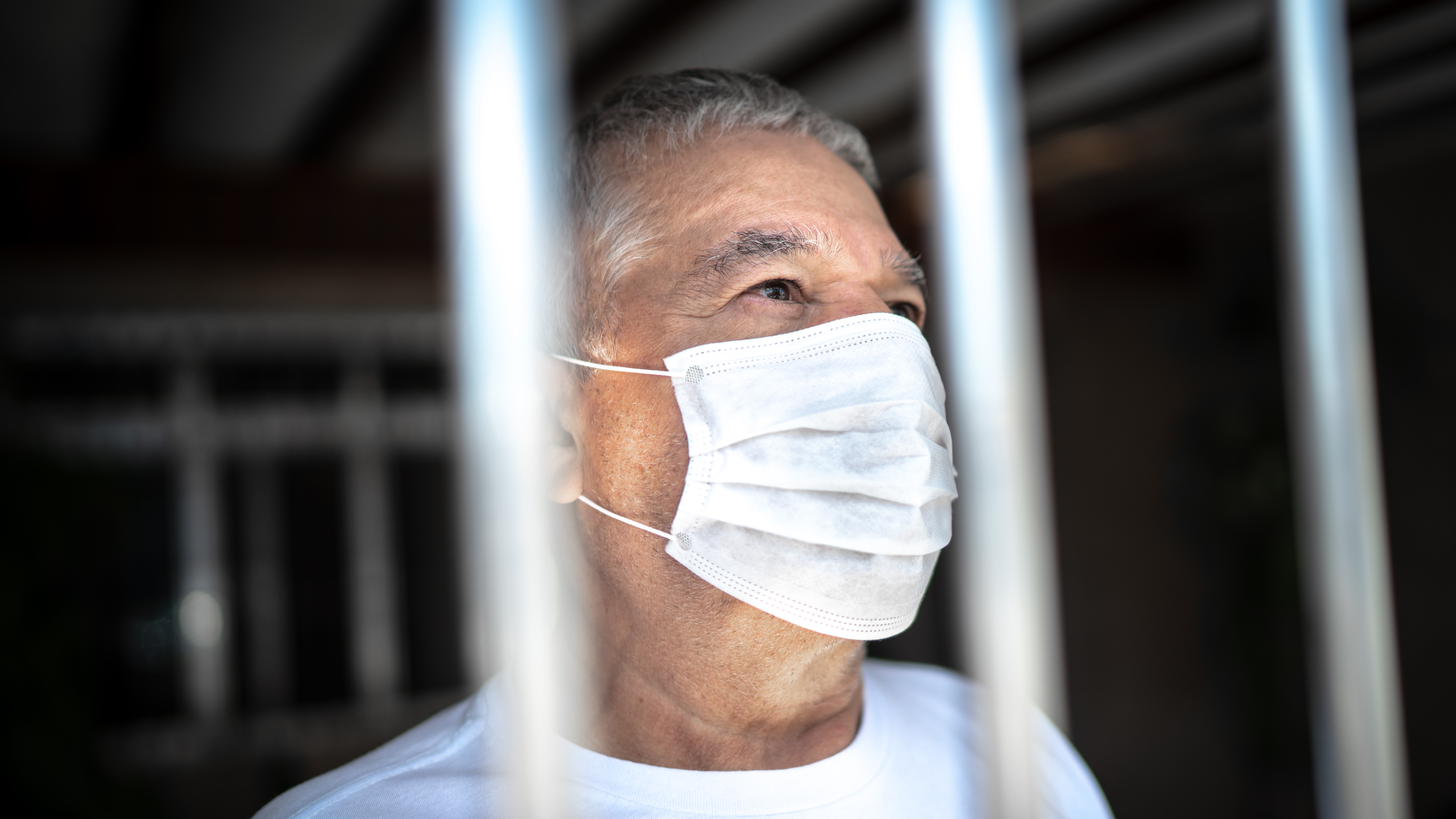 Senior man in isolation at home for virus outbreak looking through window Senior man in isolation at home for virus outbreak looking through window